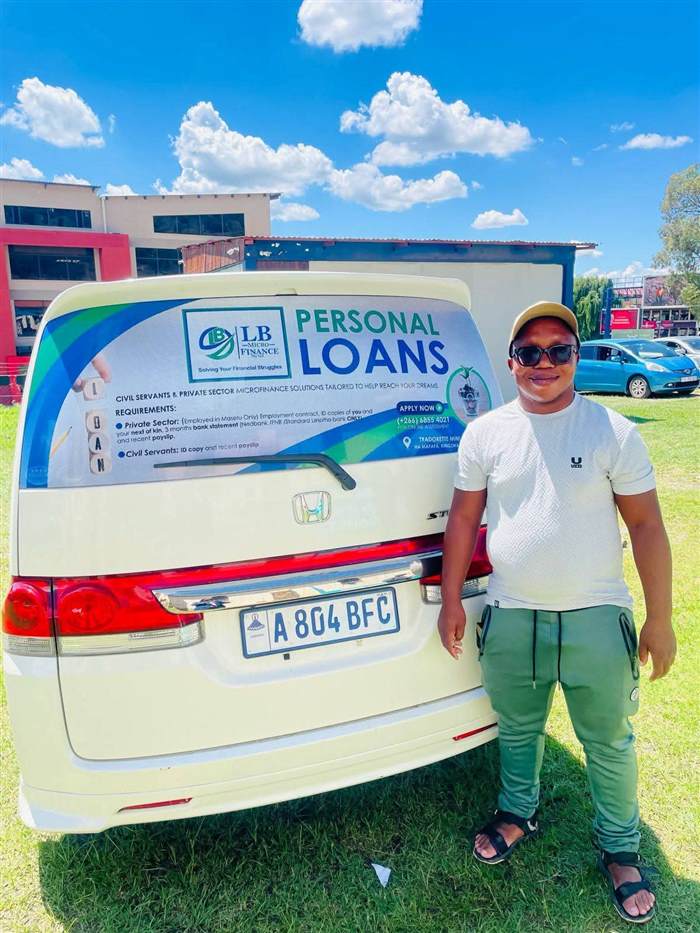LB Microfinance representative beside branded vehicle